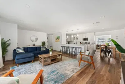 Step into this bright, open-concept living space featuring stylish furnishings, warm wood floors, and seamless flow to the kitchen and dining area. Perfect for entertaining or relaxing, with modern finishes, ample seating.