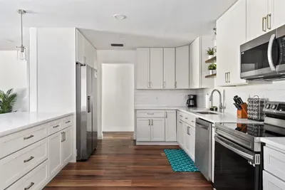 Beautifully updated—this kitchen shines with crisp white cabinetry, stainless steel appliances, and warm wood floors. Plenty of counter space and smart storage make cooking effortless, while the clean modern design is perfect for entertaining.