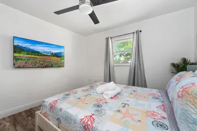 Cozy queen bedroom with a fun coastal vibe! Enjoy a comfortable bed with fresh linens, ceiling fan, and wall-mounted TV for relaxing nights in. Bright, clean, and inviting—perfect for couples, friends, or anyone needing a peaceful place to recharge.