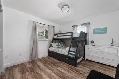 This spacious bedroom features a fun bunk bed setup plus an additional bed, offering plenty of sleeping space. Bright, clean, and comfortable with warm wood floors and storage—ideal for groups who want everyone together.