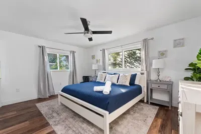 Relax in this bright and beautifully styled king bedroom! Featuring crisp linens, cozy accents, warm wood floors, and plenty of natural light. A ceiling fan adds comfort, making this peaceful retreat the perfect place to recharge after a day of fun.