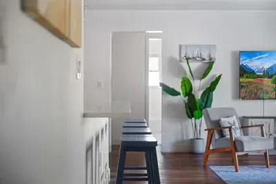 This open layout features a spacious breakfast bar with seating, warm wood floors, and stylish décor throughout. Perfect for morning coffee, casual meals, or hosting guests with effortless flow from kitchen to living space.