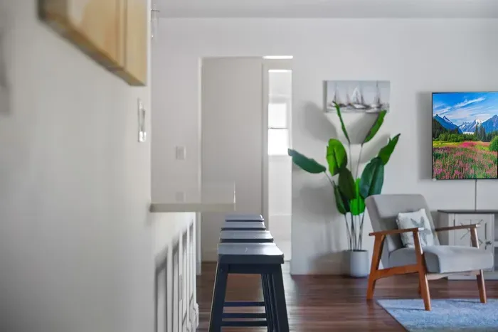This open layout features a spacious breakfast bar with seating, warm wood floors, and stylish décor throughout. Perfect for morning coffee, casual meals, or hosting guests with effortless flow from kitchen to living space.