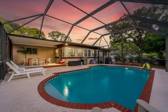 Relax in this beautiful screened-in pool oasis! Sparkling turquoise water, brick-trimmed deck, comfy loungers, and a covered patio for outdoor dining. Perfect for sunset swims, family fun, and bug-free Florida evenings—your private retreat awaits!