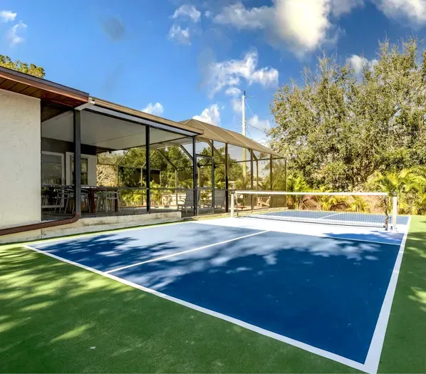 Serve, rally, and relax in your own backyard paradise! This private pickleball court sits beside a spacious screened patio with tropical landscaping and sunny skies—perfect for entertaining, staying active, and enjoying Florida living year-round.