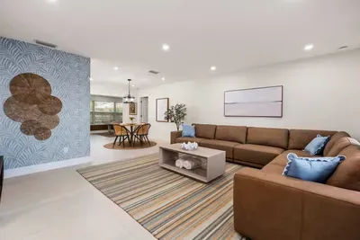 Gather and unwind in this spacious open-concept living area featuring cozy sectional seating, stylish coastal décor, and seamless flow into the dining and game spaces.