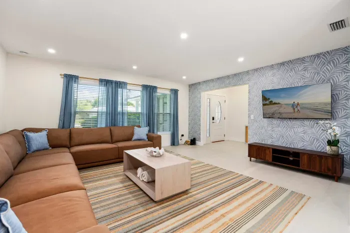 Stretch out and relax in this spacious modern living room featuring oversized sectional seating, stylish décor, and plenty of natural light. Perfect for movie nights, family gatherings, or unwinding after a day by the pool or beach.