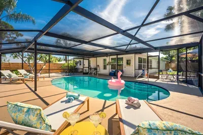 Soak up the ultimate vacation vibes in this stunning screened-in pool oasis featuring crystal-clear water, tropical surroundings, and plenty of lounge seating.