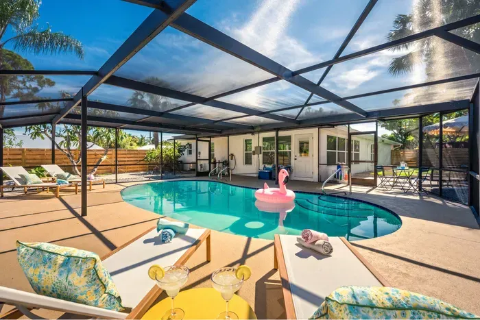 Soak up the ultimate vacation vibes in this stunning screened-in pool oasis featuring crystal-clear water, tropical surroundings, and plenty of lounge seating.