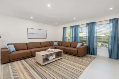 Unwind in this bright and spacious living area featuring oversized sectional sofas, soft natural light, and modern coastal décor. Perfect for movie nights, relaxing after the beach, or gathering comfortably with family and friends.