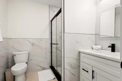 Freshen up in this sleek and modern bathroom featuring a glass walk-in shower, elegant marble-style finishes, and bright contemporary design. Thoughtfully stocked and beautifully styled for a clean, relaxing, spa-like experience during your stay.