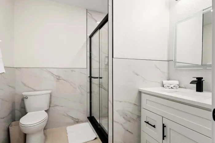 Freshen up in this sleek and modern bathroom featuring a glass walk-in shower, elegant marble-style finishes, and bright contemporary design. Thoughtfully stocked and beautifully styled for a clean, relaxing, spa-like experience during your stay.