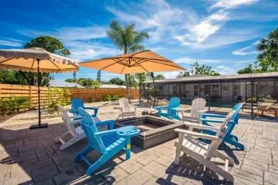 Enjoy sunny days and cozy evenings in this spacious outdoor fire pit lounge featuring comfortable Adirondack seating, tropical landscaping, and plenty of room to gather.