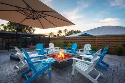 Gather around the glowing fire pit for unforgettable evenings under the stars. Featuring cozy Adirondack seating, tropical outdoor vibes, and plenty of space to relax, this backyard retreat is perfect for late-night conversations and memories.