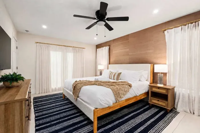 Relax in this serene and beautifully designed bedroom featuring a plush king bed, warm wood accents, soft natural light, and modern coastal touches. The perfect private retreat for restful nights and peaceful vacation mornings.