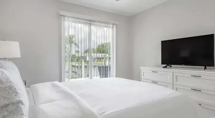 Peaceful bedroom retreat featuring a cozy queen bed, flat-screen TV, and private balcony access with calming canal views. Bright, airy, and designed for ultimate relaxation by the water.