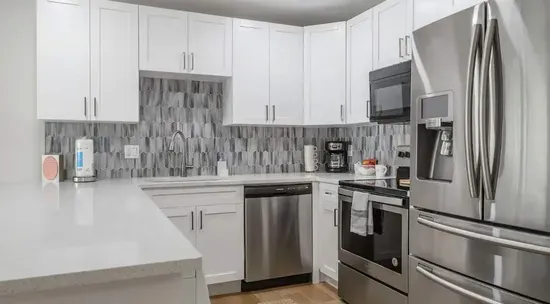 Contemporary kitchen with stainless steel appliances, sleek white cabinetry, and a stylish tile backsplash. Spacious countertops make it perfect for cooking, entertaining, or enjoying a relaxing meal at home.
