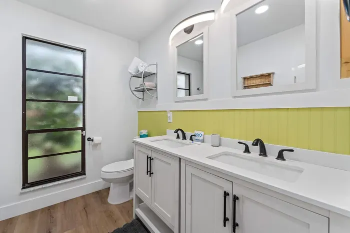 This image features a modern bathroom with a sleek double vanity in light gray, complete with elegant black faucets. The bright yellow accent wall adds a cheerful pop of color