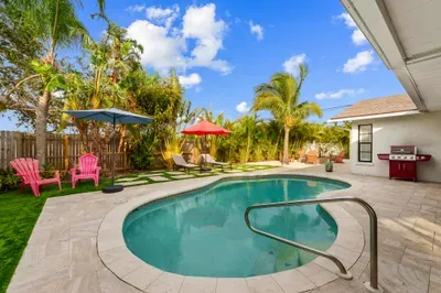 This image provides a vibrant look at the entire pool area, highlighting the lush plants and inviting loungers. The scene embodies a picturesque tropical getaway, perfect for lounging and enjoying the warm weather.