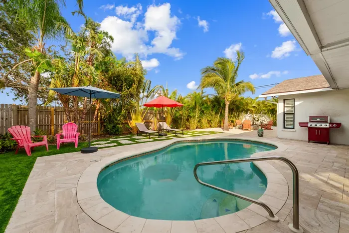 This image provides a vibrant look at the entire pool area, highlighting the lush plants and inviting loungers. The scene embodies a picturesque tropical getaway, perfect for lounging and enjoying the warm weather.