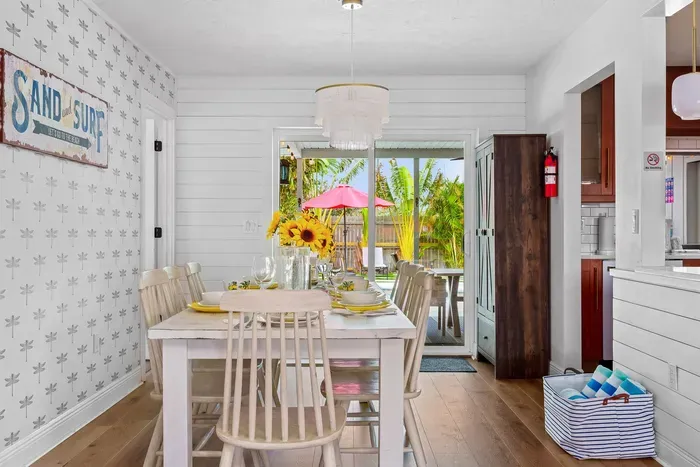 This image features a cheerful dining area with a large wooden table set for a meal. Sunflowers in a vase add a vibrant touch, while yellow plates and glasses invite guests to dine.