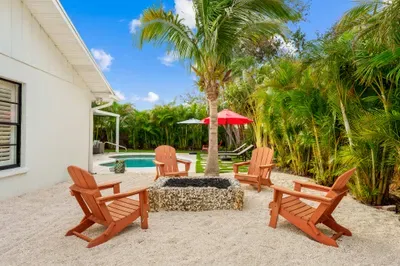 This image shows a charming outdoor space featuring four wooden Adirondack chairs arranged around a circular fire pit filled with decorative stones.