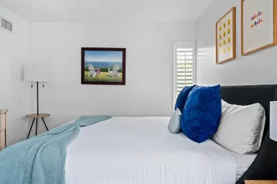 This image presents an overview of the bedroom, highlighting a comfortable bed with blue accent pillows and a decorative throw.