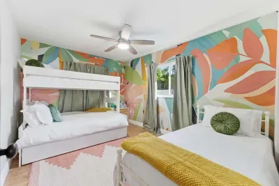 This vibrant bedroom features a playful tropical mural, cozy twin and bunk beds, and sunny decor. A fun, colorful retreat where kids (and kids at heart) can rest, relax, and dream of beach adventures.
