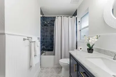 Bright and modern bathroom featuring navy cabinetry, marble counters, and striking blue tile shower. Elegant finishes and soft lighting create a clean, calming retreat.