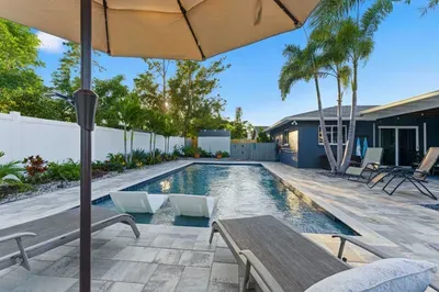 Enjoy resort-style living in this private backyard featuring a sparkling pool, palm trees, and comfy loungers. Perfect for sunbathing, swimming, or relaxing under the shade—your tropical escape awaits.