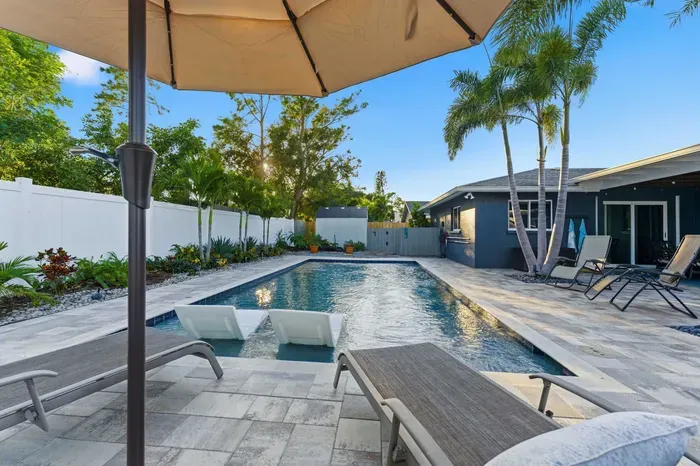 Enjoy resort-style living in this private backyard featuring a sparkling pool, palm trees, and comfy loungers. Perfect for sunbathing, swimming, or relaxing under the shade—your tropical escape awaits.