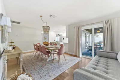 Elegant dining space with blush tones, a statement chandelier, and seamless flow to the outdoor patio. Gather for memorable meals or enjoy breezy indoor-outdoor living in this beautifully styled, sunlit setting.
