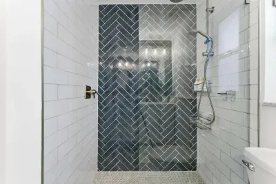 Modern walk-in shower featuring sleek glass doors, bold blue herringbone tiles, and elegant chrome fixtures. A spa-inspired space designed for relaxation and rejuvenation.