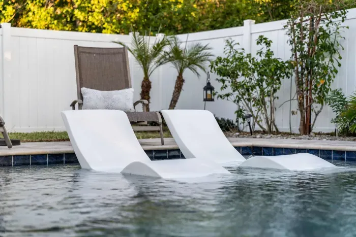 Sink into serenity—enjoy poolside perfection with in-water loungers designed for ultimate relaxation. Surrounded by lush greenery and privacy fencing, this tranquil spot is your own slice of paradise to unwind, sunbathe, or sip something cool.