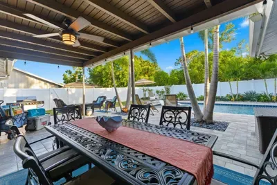 Spacious covered patio with elegant dining set, ceiling fan, and poolside views. Perfect for outdoor meals, games, or relaxing in the shade while enjoying the Florida sunshine.