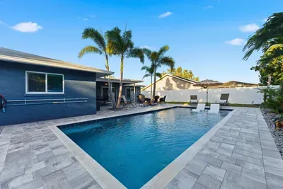 Gorgeous backyard with a sparkling pool, palm trees, and stylish lounge seating. Ideal for sunny days and evening swims—your private tropical getaway awaits.