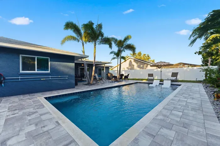 Gorgeous backyard with a sparkling pool, palm trees, and stylish lounge seating. Ideal for sunny days and evening swims—your private tropical getaway awaits.
