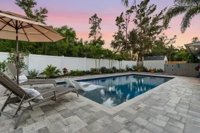 Peaceful backyard escape with a sparkling pool, lush landscaping, and sunset views. Lounge beneath the umbrella or take a dip—perfect for unwinding in your private tropical paradise.