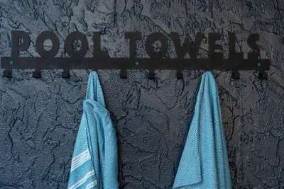 Thoughtful poolside detail with a stylish “Pool Towels” rack and cozy blue towels—perfect for drying off after a refreshing swim or lounging by the water.