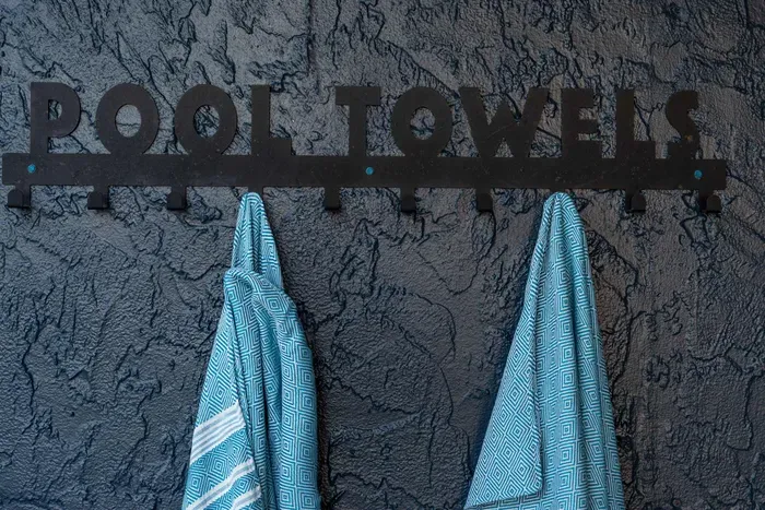 Thoughtful poolside detail with a stylish “Pool Towels” rack and cozy blue towels—perfect for drying off after a refreshing swim or lounging by the water.