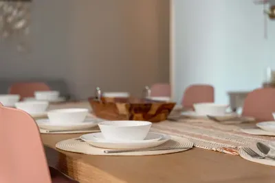 Beautifully set dining table with blush chairs, woven placemats, and modern dishware creates an inviting space for shared meals. Warm tones and natural textures make every gathering feel stylish and relaxed.