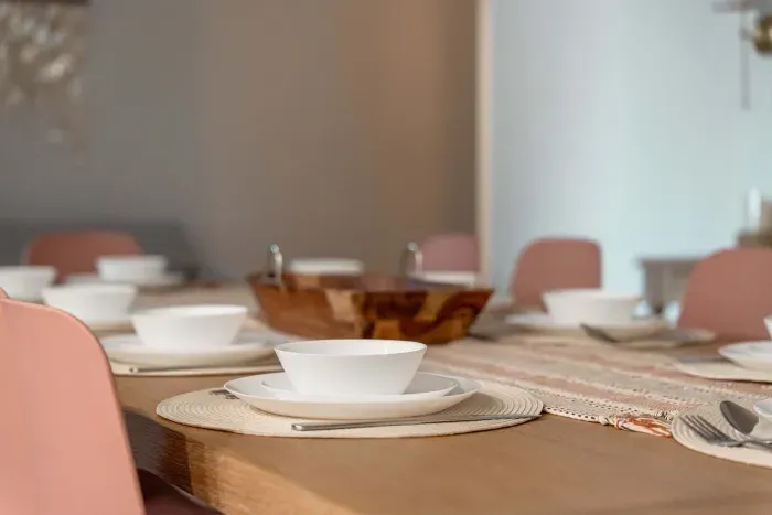 Beautifully set dining table with blush chairs, woven placemats, and modern dishware creates an inviting space for shared meals. Warm tones and natural textures make every gathering feel stylish and relaxed.