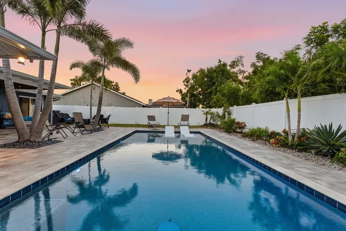 Tranquil poolside paradise framed by palm trees and sunset skies. Perfect for relaxing swims or evening gatherings—your own private retreat with tropical charm.