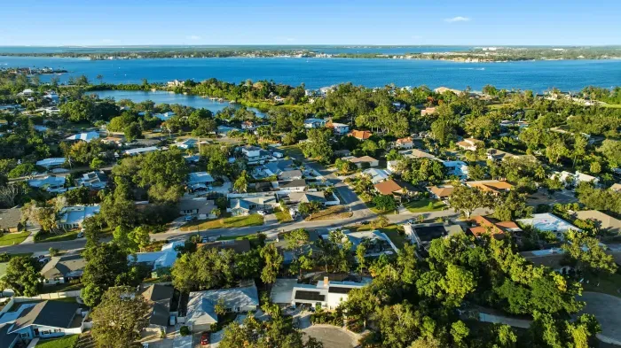 Beautiful aerial view of a coastal neighborhood surrounded by lush greenery and sparkling blue waters—perfectly situated for beach days, sunset strolls, and a relaxing coastal getaway.