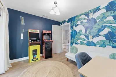 This stylish lounge mixes tropical flair with retro fun—complete with classic arcade machines, bold palm-print walls, and comfy seating. Futon bed that converts into another room