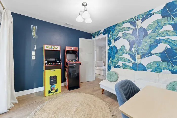 This stylish lounge mixes tropical flair with retro fun—complete with classic arcade machines, bold palm-print walls, and comfy seating. Futon bed that converts into another room