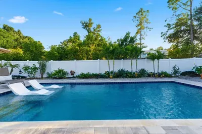 Inviting backyard pool surrounded by tropical greenery and in-water loungers. Perfect for cooling off or sunbathing in a private, resort-style setting with total relaxation.