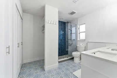 Stylish bathroom with vibrant blue tile flooring and a bold herringbone shower design. Bright, modern, and spacious—this refreshing space brings spa-like comfort to your stay.