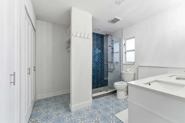 Stylish bathroom with vibrant blue tile flooring and a bold herringbone shower design. Bright, modern, and spacious—this refreshing space brings spa-like comfort to your stay.