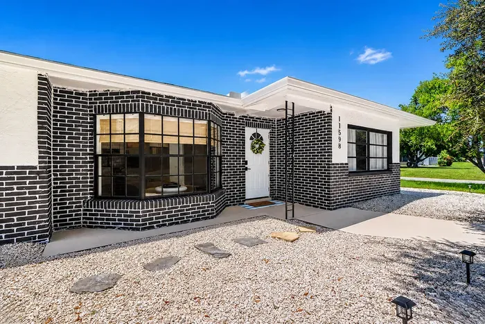 Modern black brick, industrial-style windows, and a bay window that looks straight into the living room — the house has real architecture behind the vacation photos.